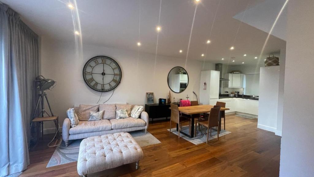 a living room with a couch and a table and a clock at Modern and Unique Home in London, Chiswick in London