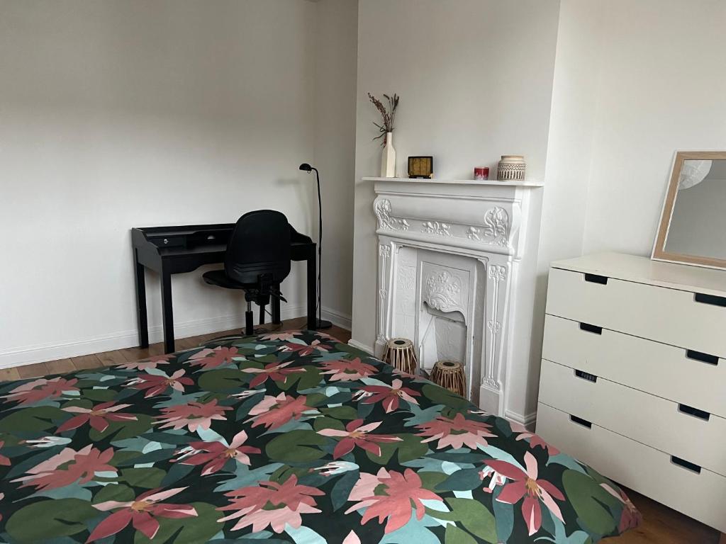 a bedroom with a bed with a floral blanket and a desk at Ilford Hidden Gem in Ilford