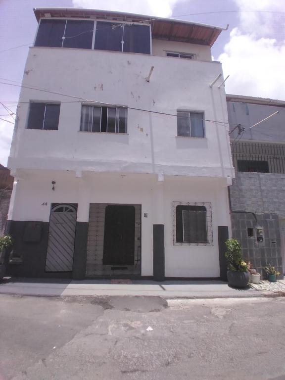 - un bâtiment blanc avec des fenêtres noires dans une rue dans l'établissement Hospedagem domiciliar casa do Jorge Rua 44 Nossa Senhora da Angústia Itapuã, à Salvador