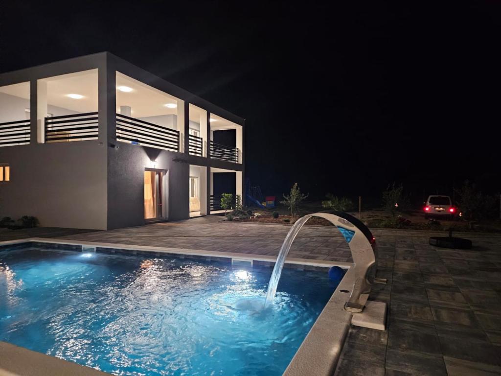 a swimming pool in front of a house at night at Villa JaNi in Donja Jagodnja