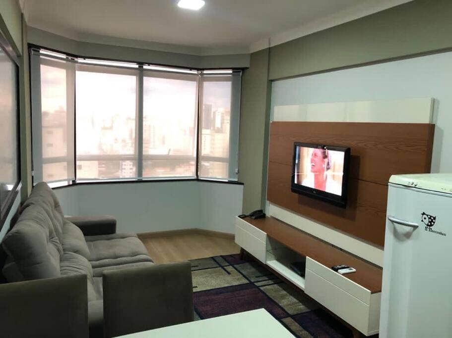a living room with a couch and a tv at Flat mobiliado em Campinas - Ap 124 L Hirondelle in Campinas