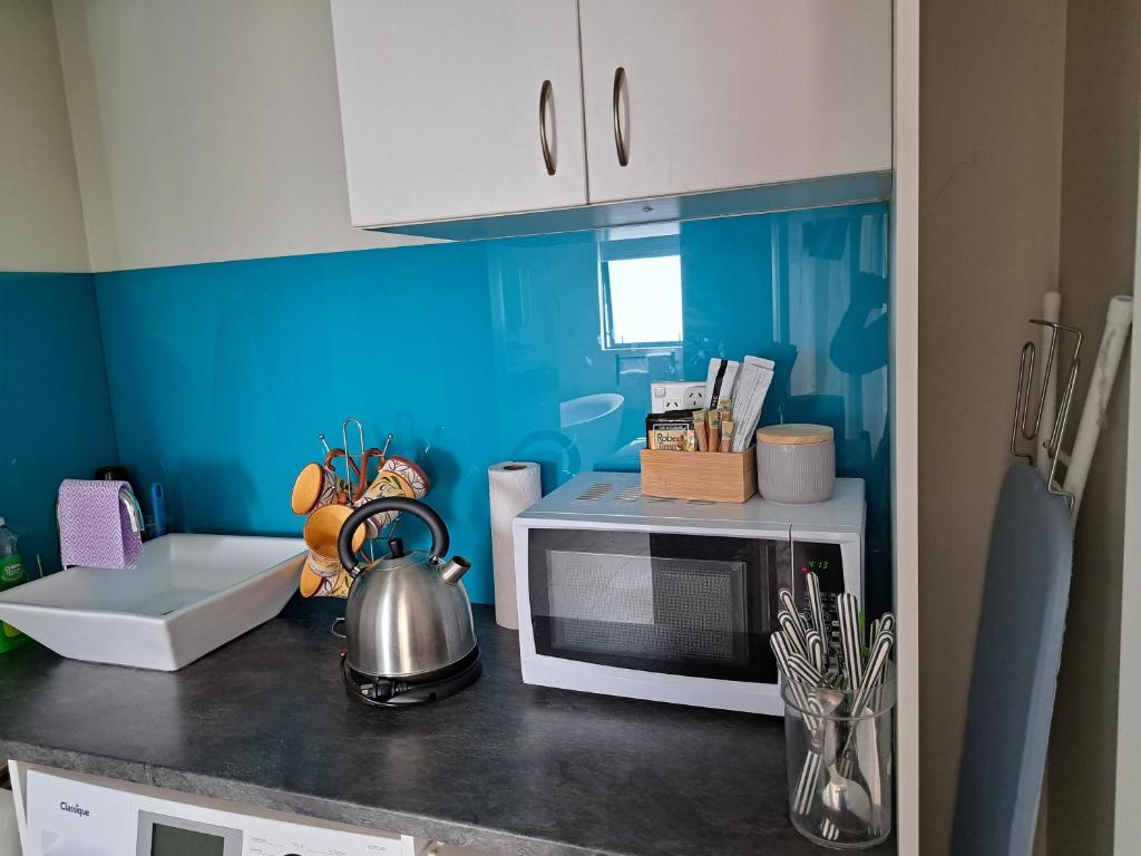 cocina con paredes azules y microondas en una encimera en Sunbrae Beach Two rooms en Mount Maunganui