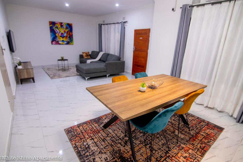 een woonkamer met een houten tafel en stoelen bij White Rhino apartments & tours in Livingstone