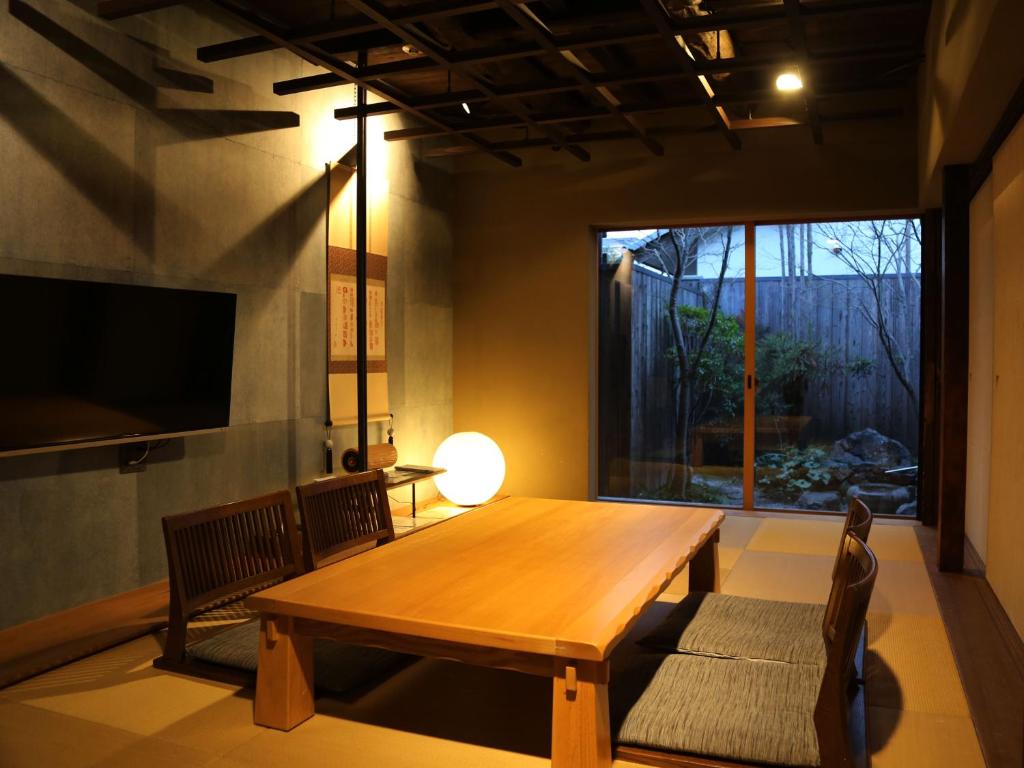 comedor con mesa de madera y ventana grande en Zen Machiya Inn, en Kioto
