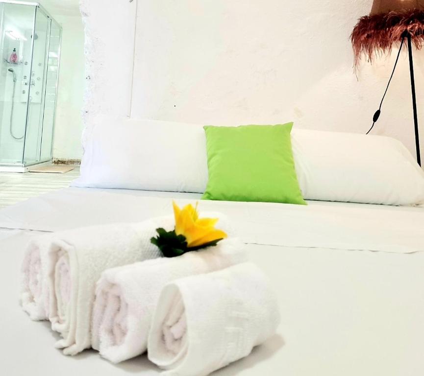 Una cama blanca con toallas y una flor amarilla. en Apartamento Cueva La Torre, en Aldaia