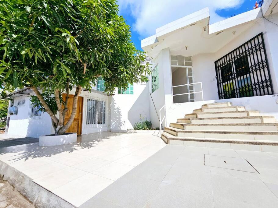 a white house with stairs and a tree at Departamento amoblado excelente para familias in Puerto Baquerizo Moreno