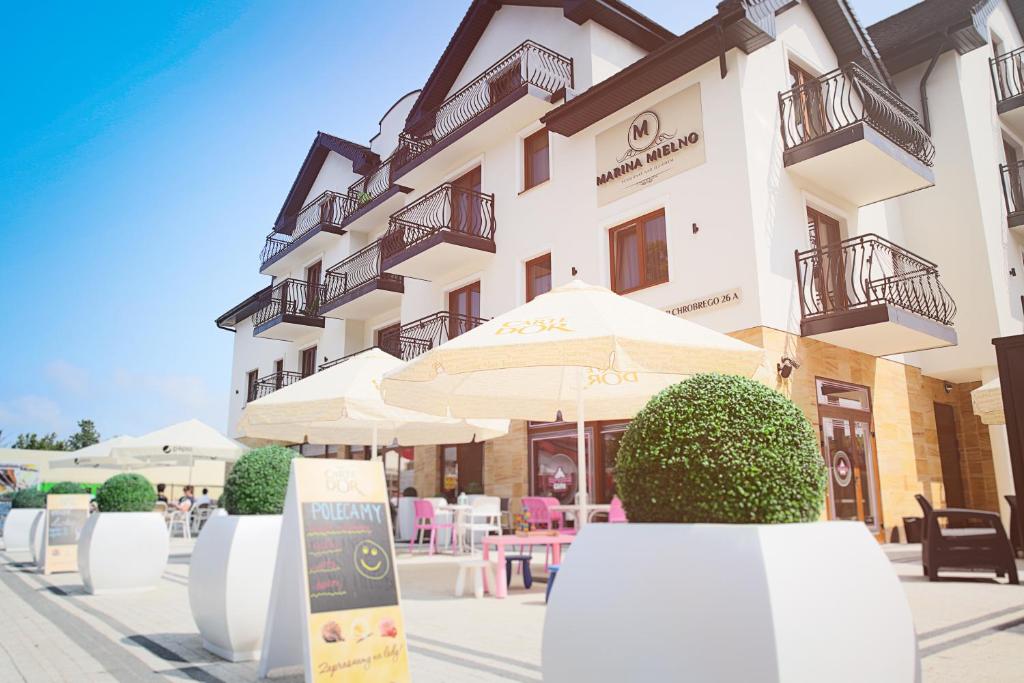 a building with an umbrella and tables and chairs at Marina Mielno z widokiem na jezioro in Mielno