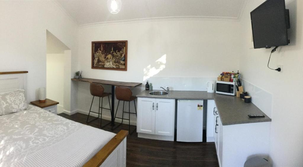 eine kleine Küche mit einem Waschbecken und ein Bett in einem Zimmer in der Unterkunft Studio on Denne in Tamworth