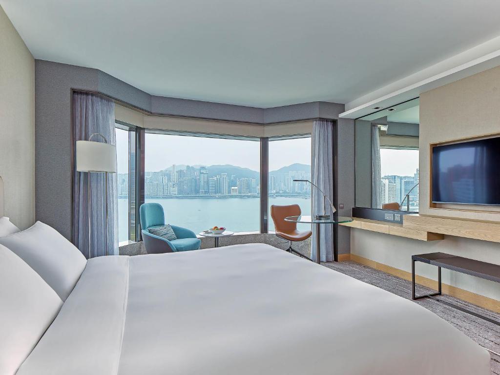 香港にあるニュー ワールド ミレニアム 香港 ホテルの大きなベッドと大きな窓が備わるホテルルームです。