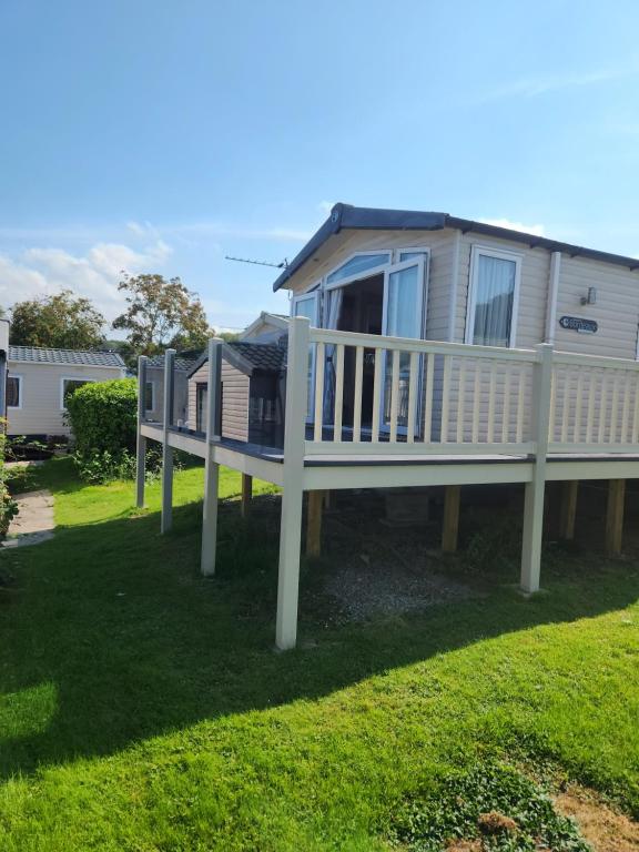 a mobile home with a deck on a lawn at Swn y Mor (Glamorgan 23) in New Quay