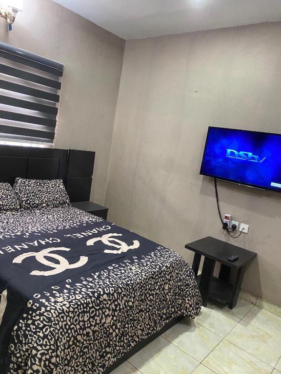 a bedroom with a bed and a flat screen tv at DIVINE VILLA AND RESORTS HOTEL GUEST House 15 mins Near Michael Okpara University Sam Mbakwe Airport in Umuhu