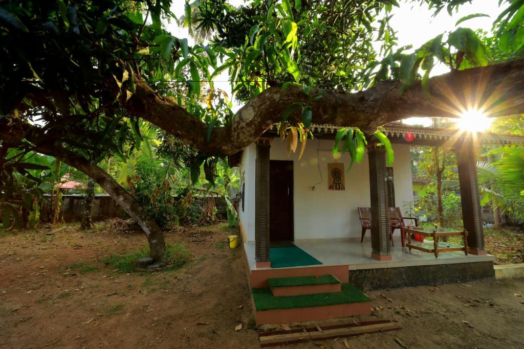 una pequeña casa con un árbol delante en Appu's Abode en Kollam