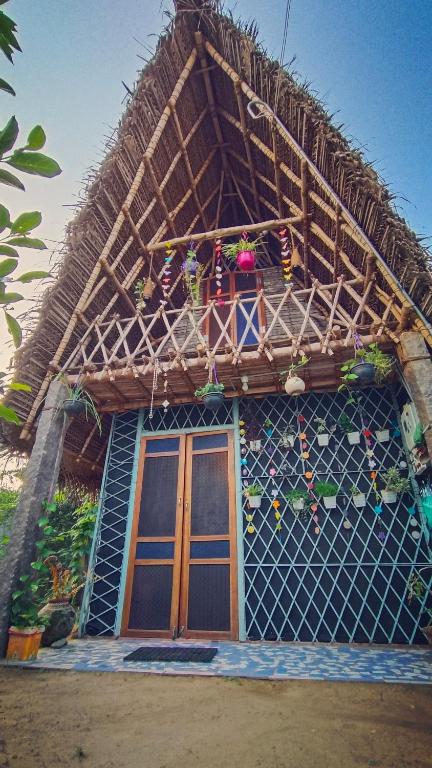a house with a thatched roof and a balcony at Open house in Auroville