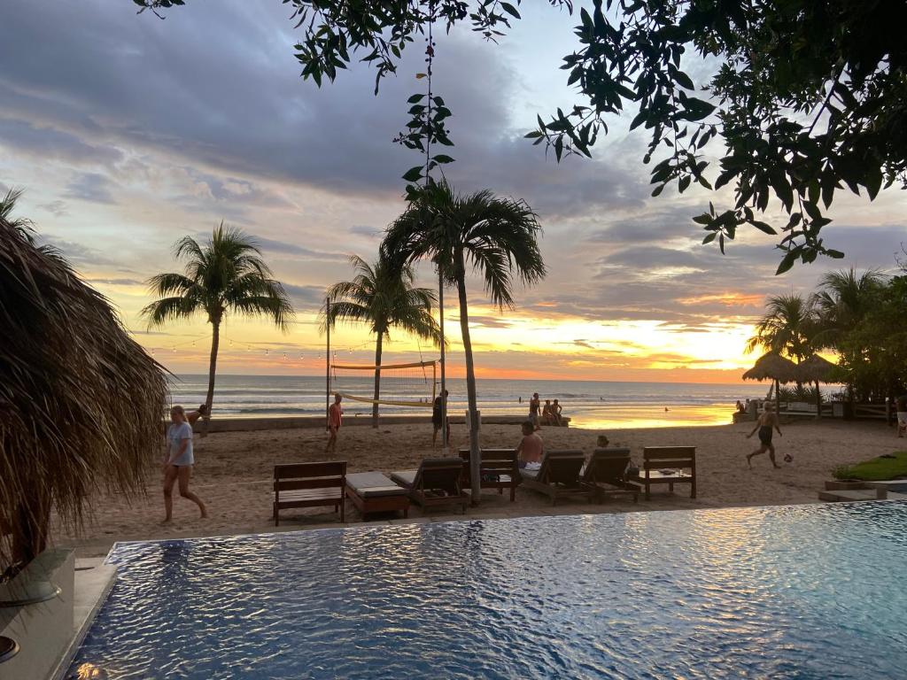 una piscina en la playa con puesta de sol en Hacienda Iguana Surf & Golf apartment, en Tola