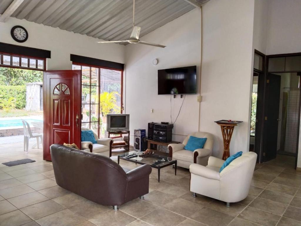 - un salon avec un canapé, des chaises et une télévision dans l'établissement La Esthera Hospedaje Rural, à Carmen de Apicalá