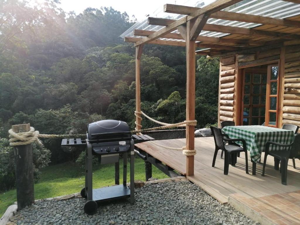 a grill on a wooden deck with a table and chairs at Glamping Villa del Bosque in Santa Rosa de Cabal