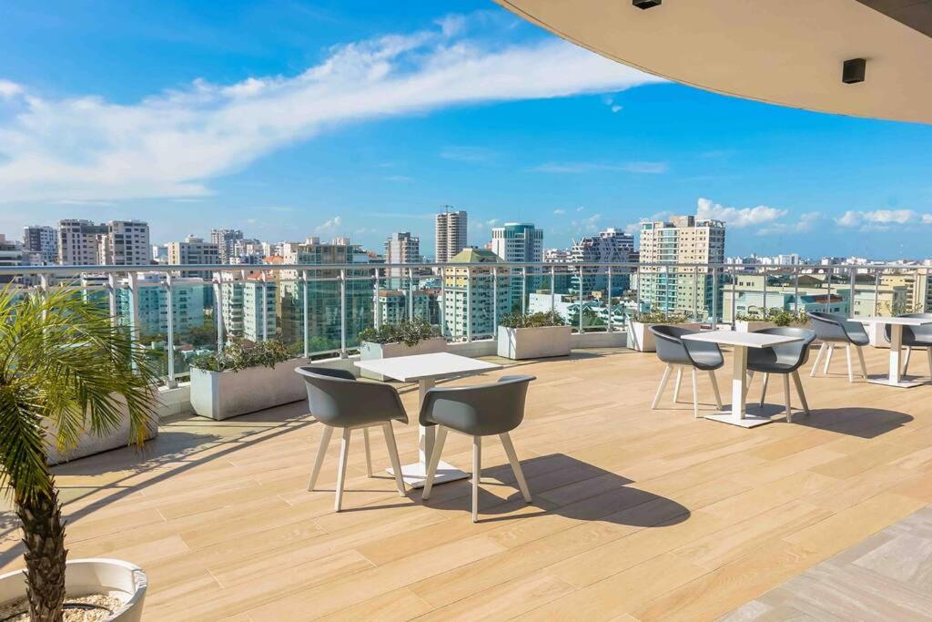 um pátio no último piso com mesas e cadeiras e um horizonte da cidade em Apartment Santo Domingo-Piantini em Santo Domingo