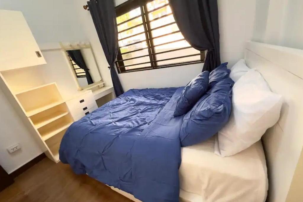 Cama azul en habitación con ventana en Unit N103 Outlook Ridge Residences, en Baguio