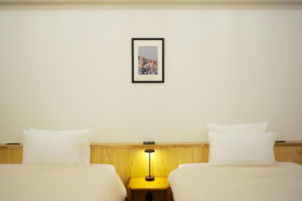東京にあるHERE.Tokyoの壁に絵が描かれた部屋のベッド2台