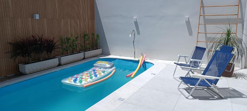 a swimming pool with a inflatable boat and two chairs at Hospedagem Sol Nascente - Pé na Areia in Arroio do Silva