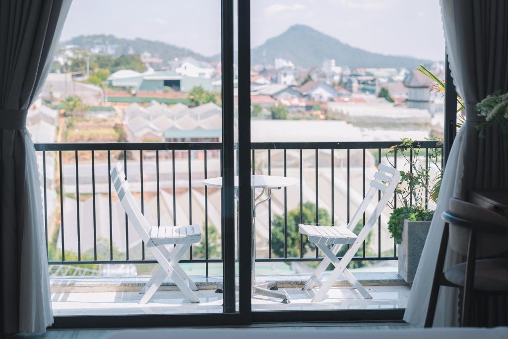 大叻的住宿－Canary Dalat Hotel，美景阳台配有两把椅子和一张桌子
