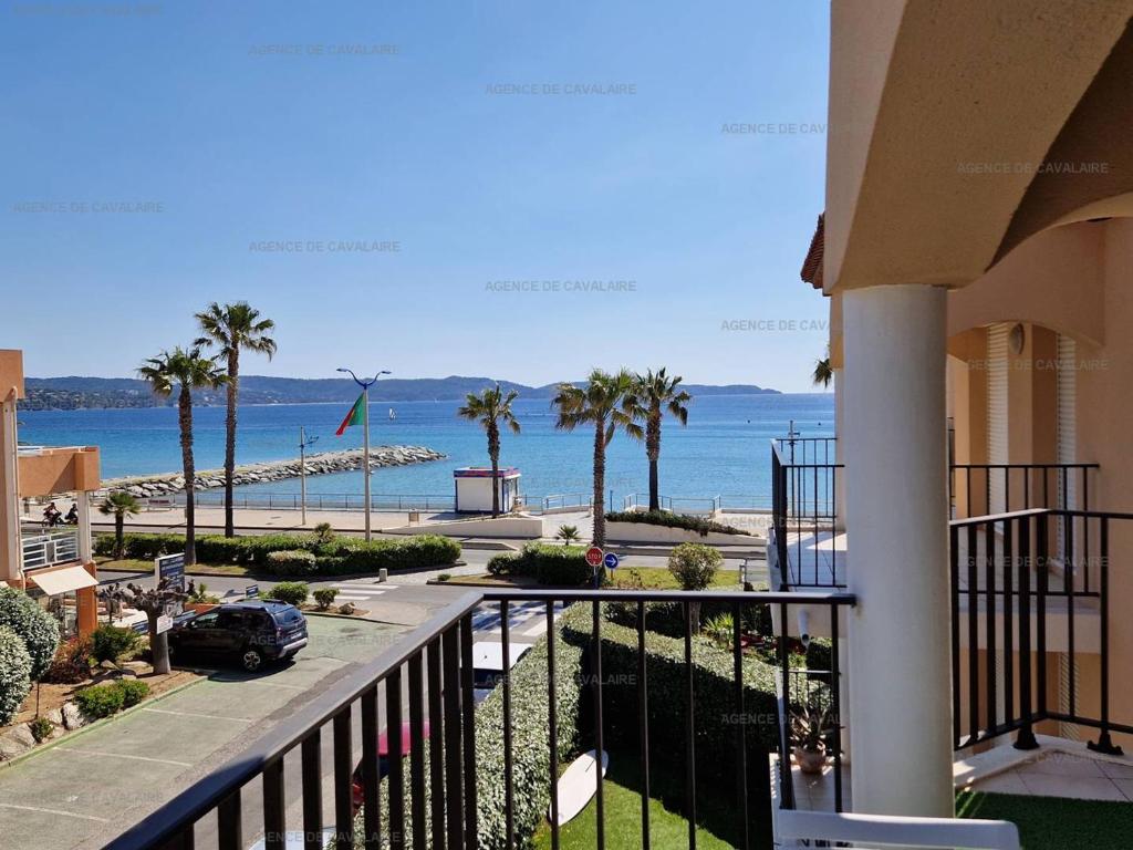 d'un balcon avec vue sur l'océan et les palmiers. dans l'établissement Beau T2 en front de mer avec clim, parking, animaux admis - FR-1-100-327, à Cavalaire-sur-Mer