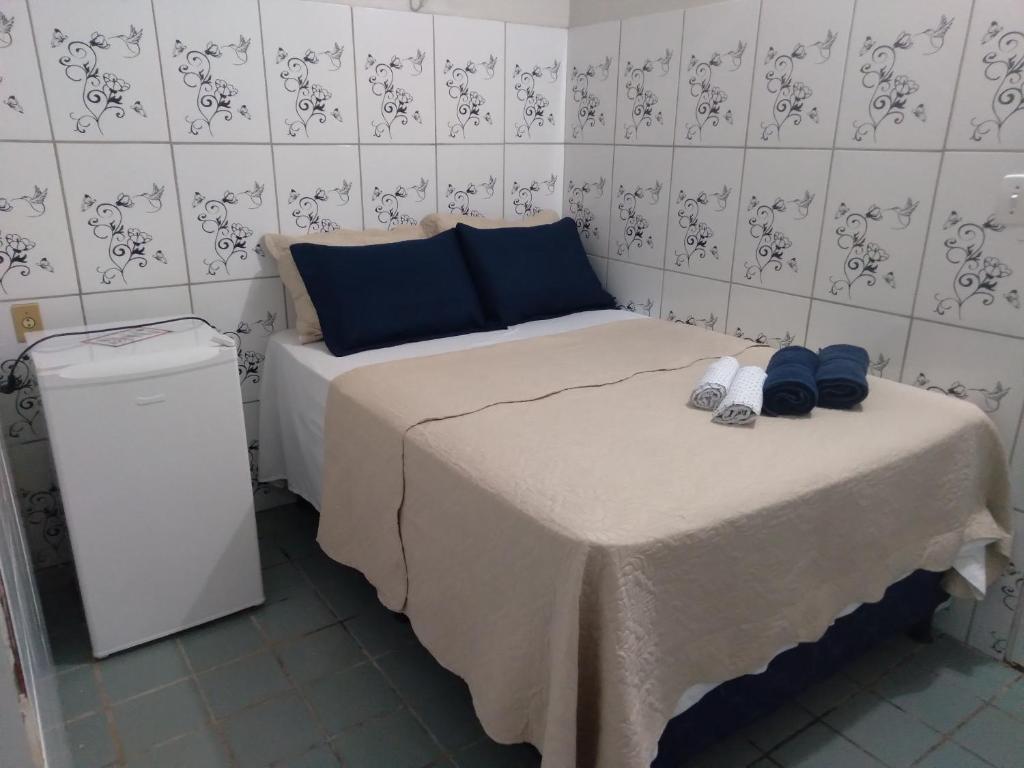 a small room with a bed with blue pillows and shoes at Pousada Pôr do Sol - Galinhos in Galinhos