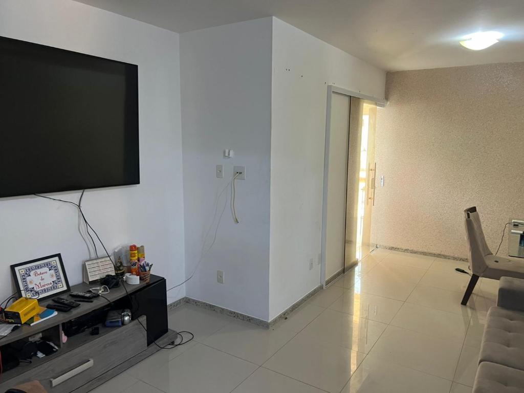 ein Wohnzimmer mit einem Flachbild-TV an der Wand in der Unterkunft Casa Condominio Fechado - Barra dos Coqueiros in Barra dos Coqueiros
