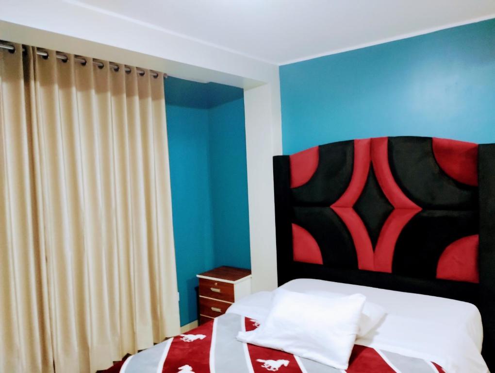 1 dormitorio con 1 cama con cabecero rojo y negro en HOSTAL TOSCANO SUITES, en El Tambo