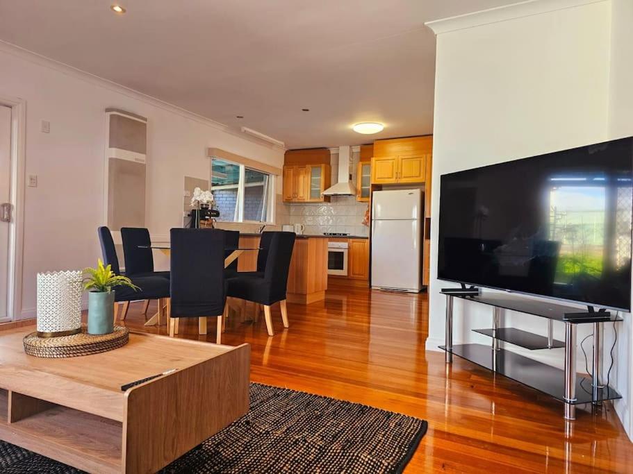 a living room with a large television and a table at Tranquil and cosy guest house in Oakleigh East
