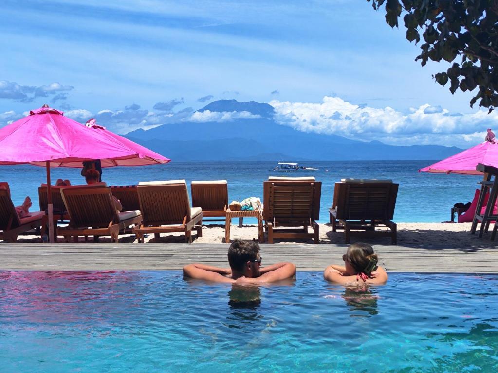 um homem e uma mulher numa piscina perto da praia em Lushy Hostel Nusa Penida em Nusa Penida