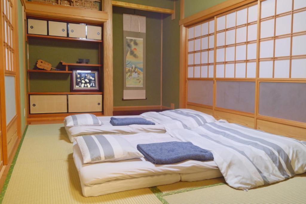 Cette chambre comprend 4 grands lits blancs. dans l'établissement 四万十川傍にある日本家屋まるごと「貸切宿　ほとり」, à Shimanto