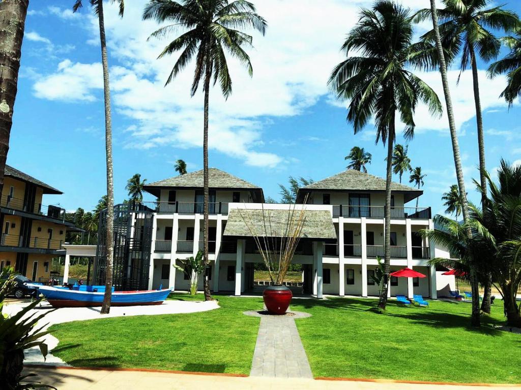 a building with palm trees in front of it at Klong Son Resortel in Ban Khlong Son