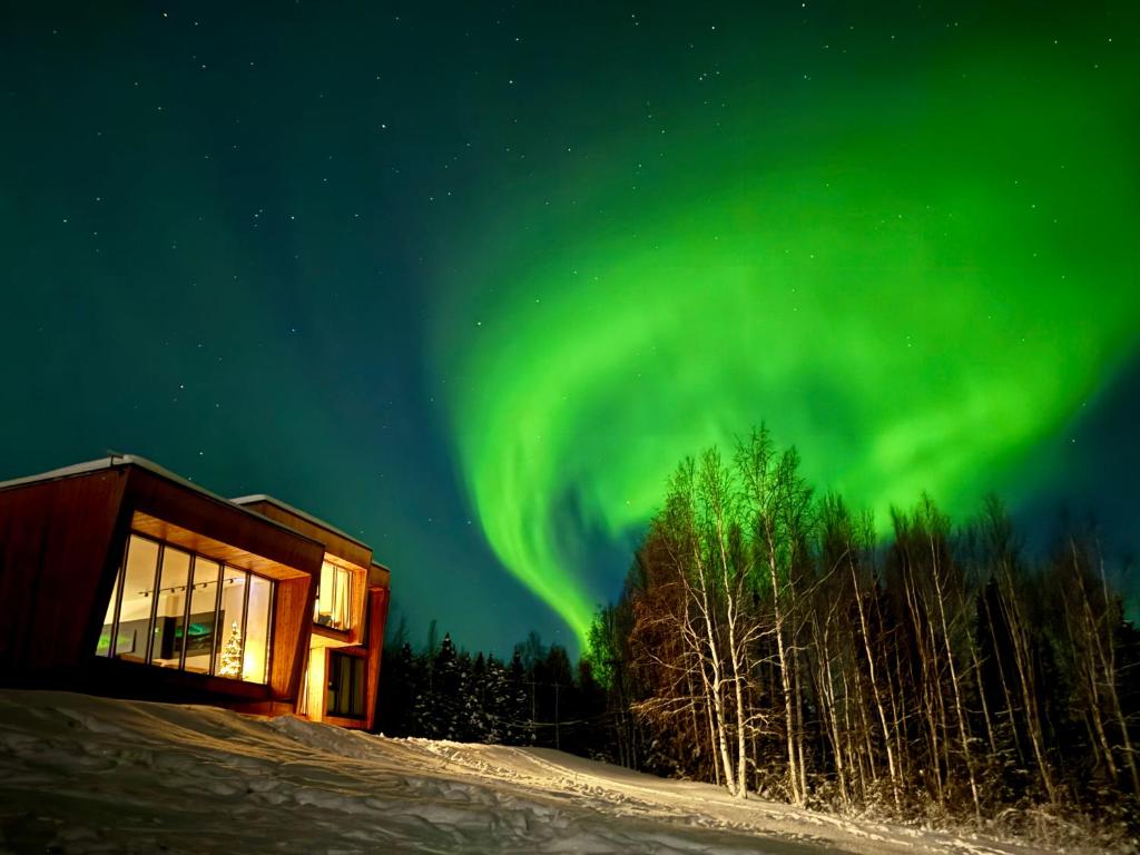 una imagen de la aurora boreal sobre una cabina en Aurora Villa, en Fairbanks