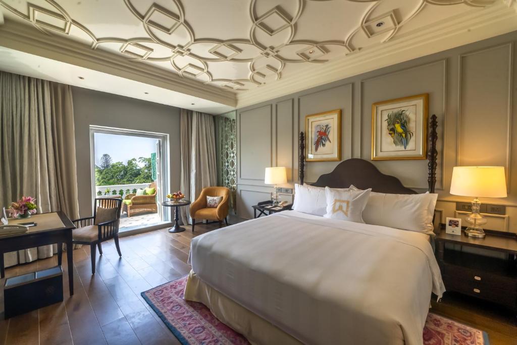 um quarto com uma cama grande e uma secretária e um quarto em ITC Windsor, a Luxury Collection Hotel, Bengaluru em Bangalore