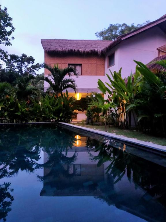 a villa with a swimming pool in front of a house at Pool House Studios in Kuta Lombok