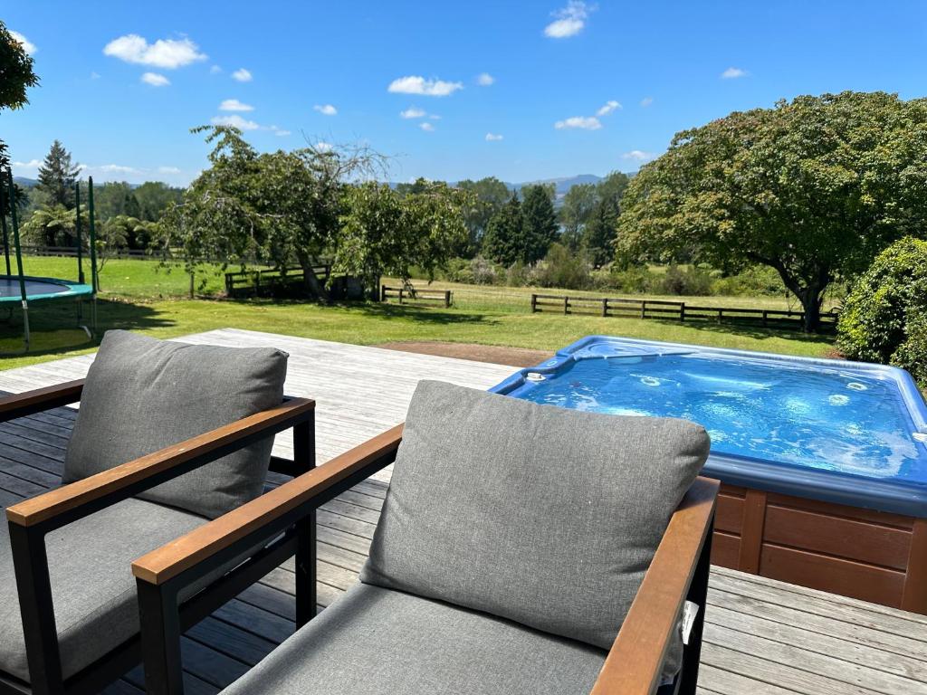 um deque com 2 cadeiras e uma piscina em Lake Holiday Home - Spa & Views em Mangakino