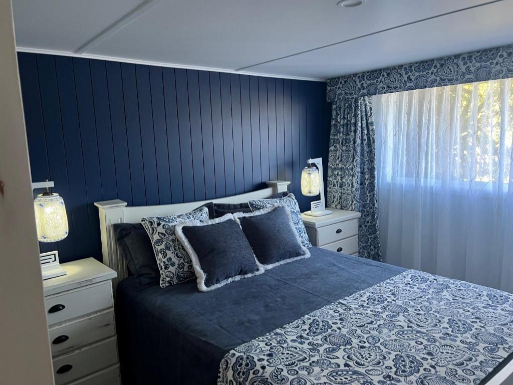 Schlafzimmer mit blauen Wänden und einem Bett mit Kissen in der Unterkunft Rainbows End in Redcliffe