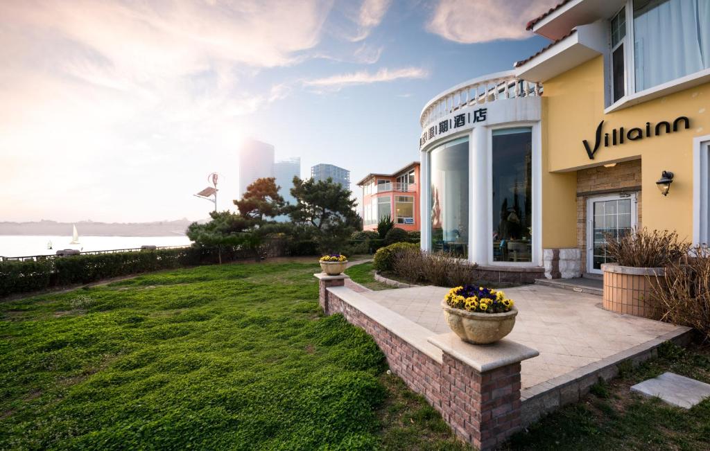 a building with a porch and a yard at Qingdao Villa Inn in Qingdao