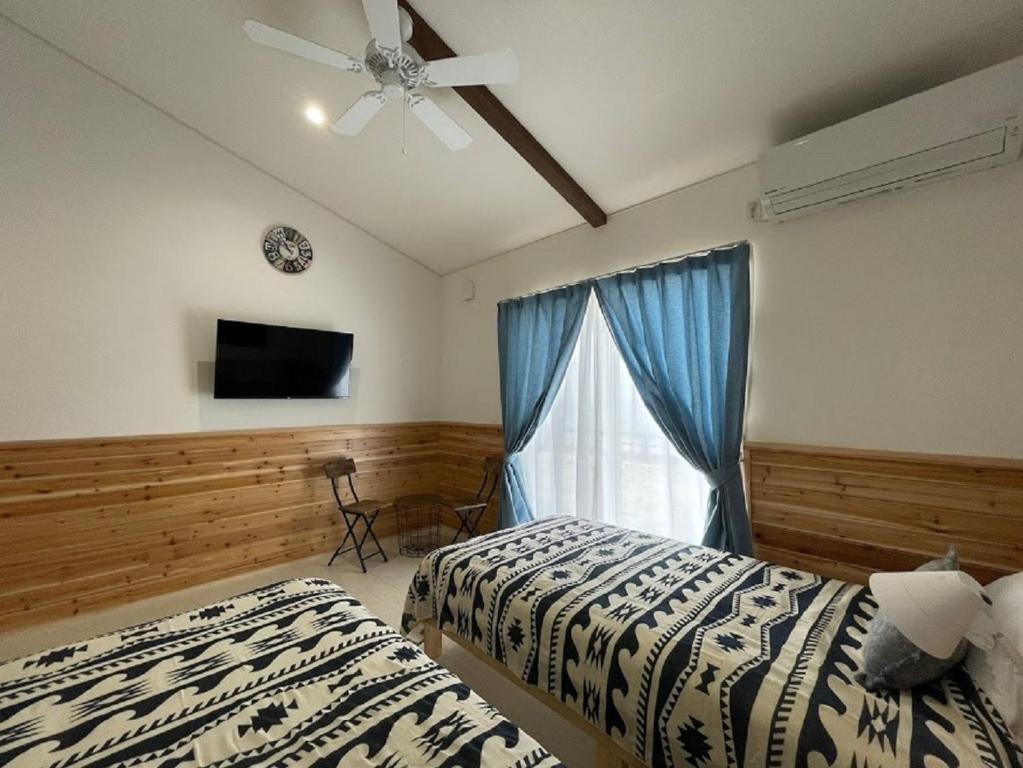 a bedroom with two beds and a window with a ceiling fan at Pension Le Passage - Vacation STAY 11300v in Tottori