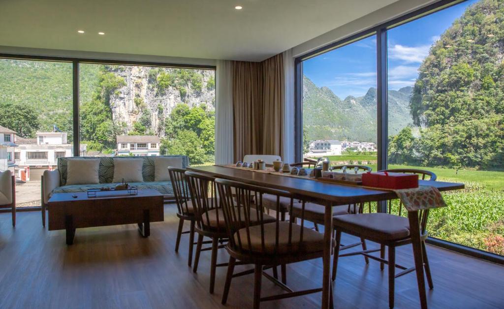 ein Wohnzimmer mit einem Tisch und Stühlen sowie einem großen Fenster in der Unterkunft Fanzhu Hotel in Xingyi