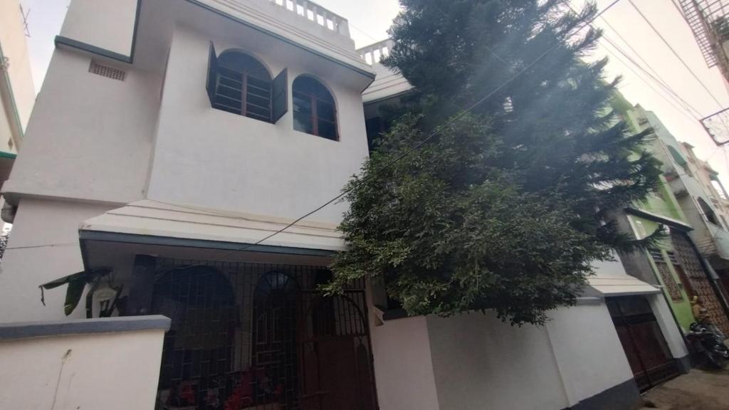 a white house with a tree in front of it at House of Rabindra Kumar in Deoghar