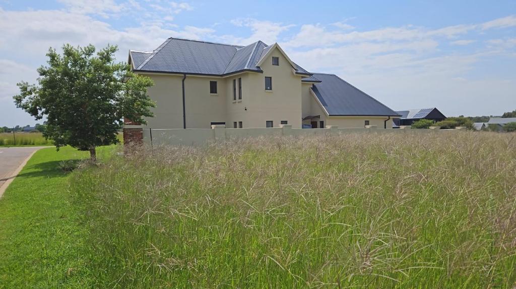 a house in a field of grass with a tree at 137 Vaal De Grace Golf Estate in Parys