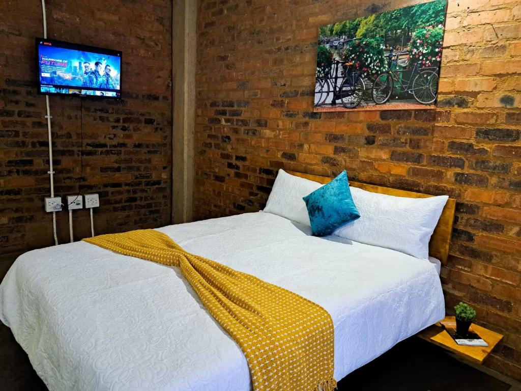 a bedroom with a bed and a tv on a brick wall at Views on main: Craftsmanship hotel in Johannesburg