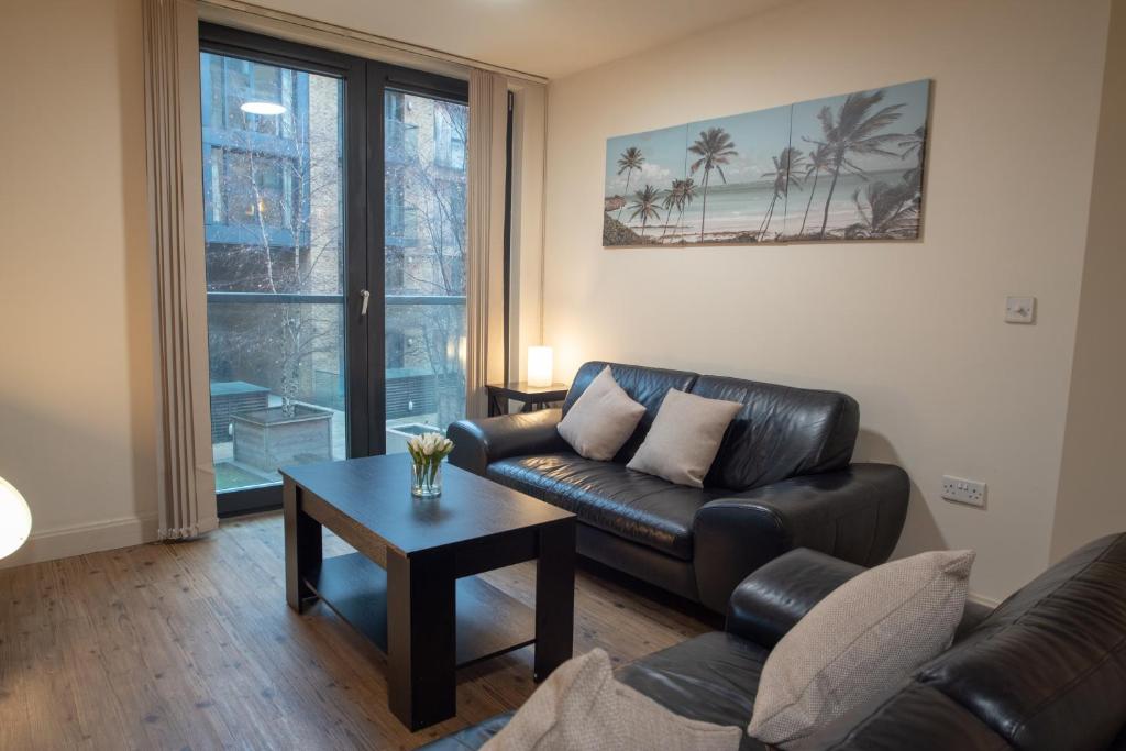 a living room with a leather couch and a table at Discover Comfort and Style - Your Elegant Stay Offers a 2-Bedroom Haven with Free Parking and Coffee! in Birmingham