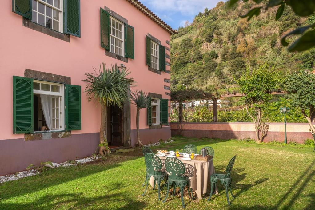 een tafel en stoelen voor een roze huis bij Casa da Fajã Alta with breakfast by An Island Apart in Jogo da Bola