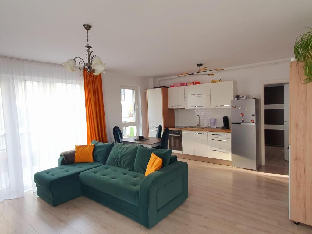 a living room with a green couch and a kitchen at River park CB in Reghin