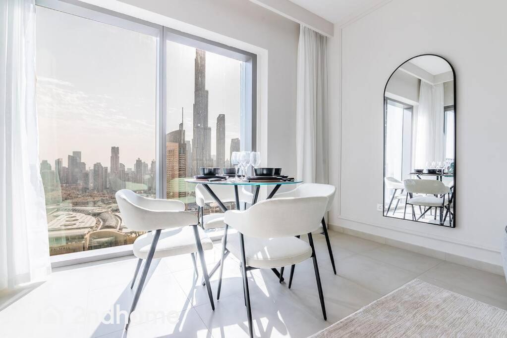 a dining room with a table and white chairs and a large window at Direct Access to Dubai Mall, Downtown Views II T1 in Dubai