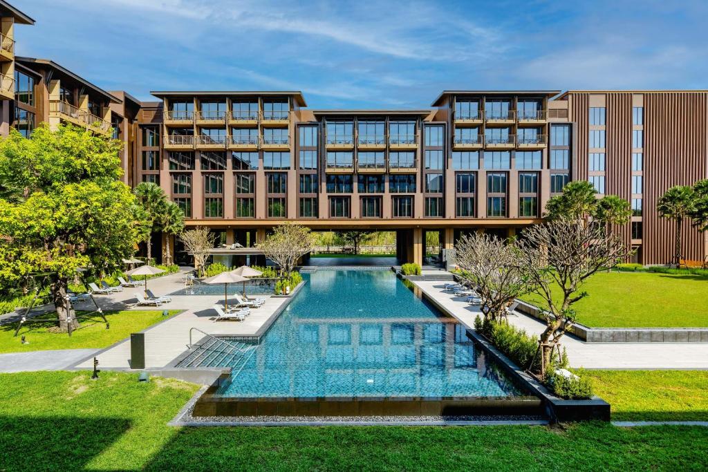 an exterior view of a building with a swimming pool at Courtyard by Marriott Bangkok Suvarnabhumi Airport in Bangkok