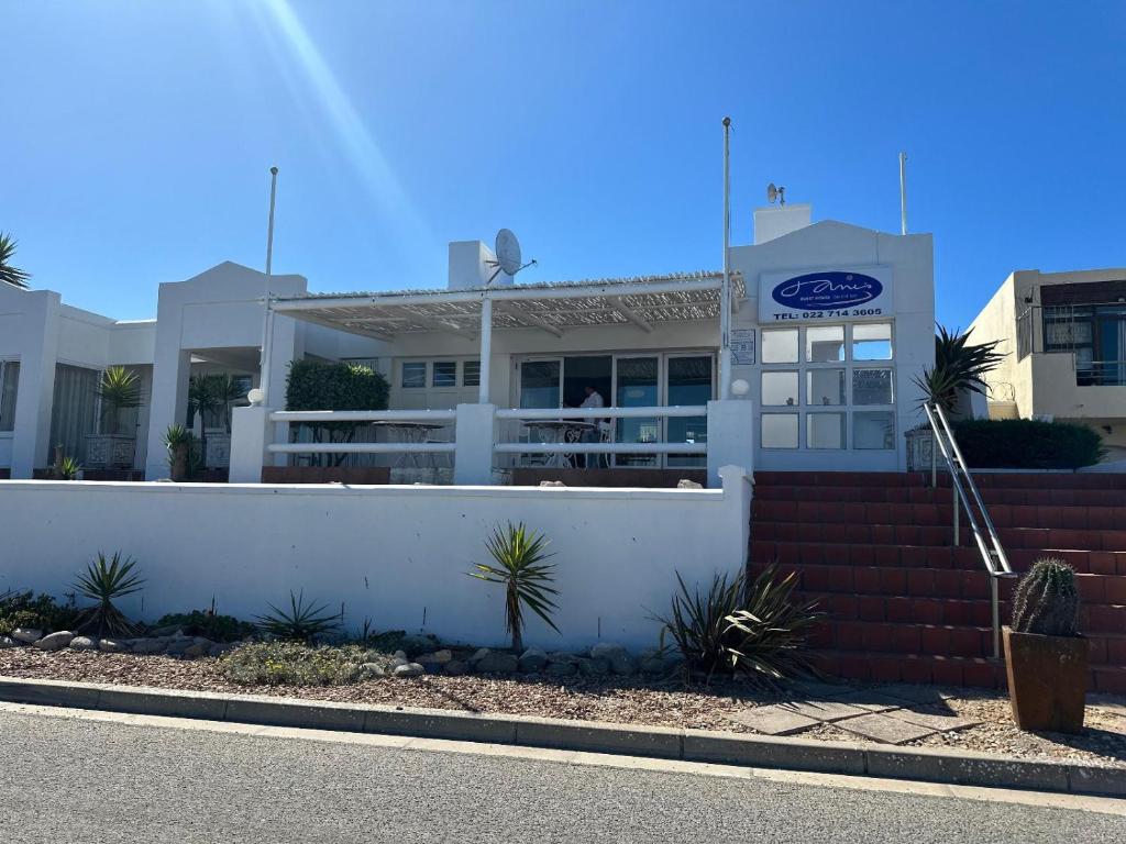 a white building with a fence in front of it at Jane's Guesthouse in Saldanha
